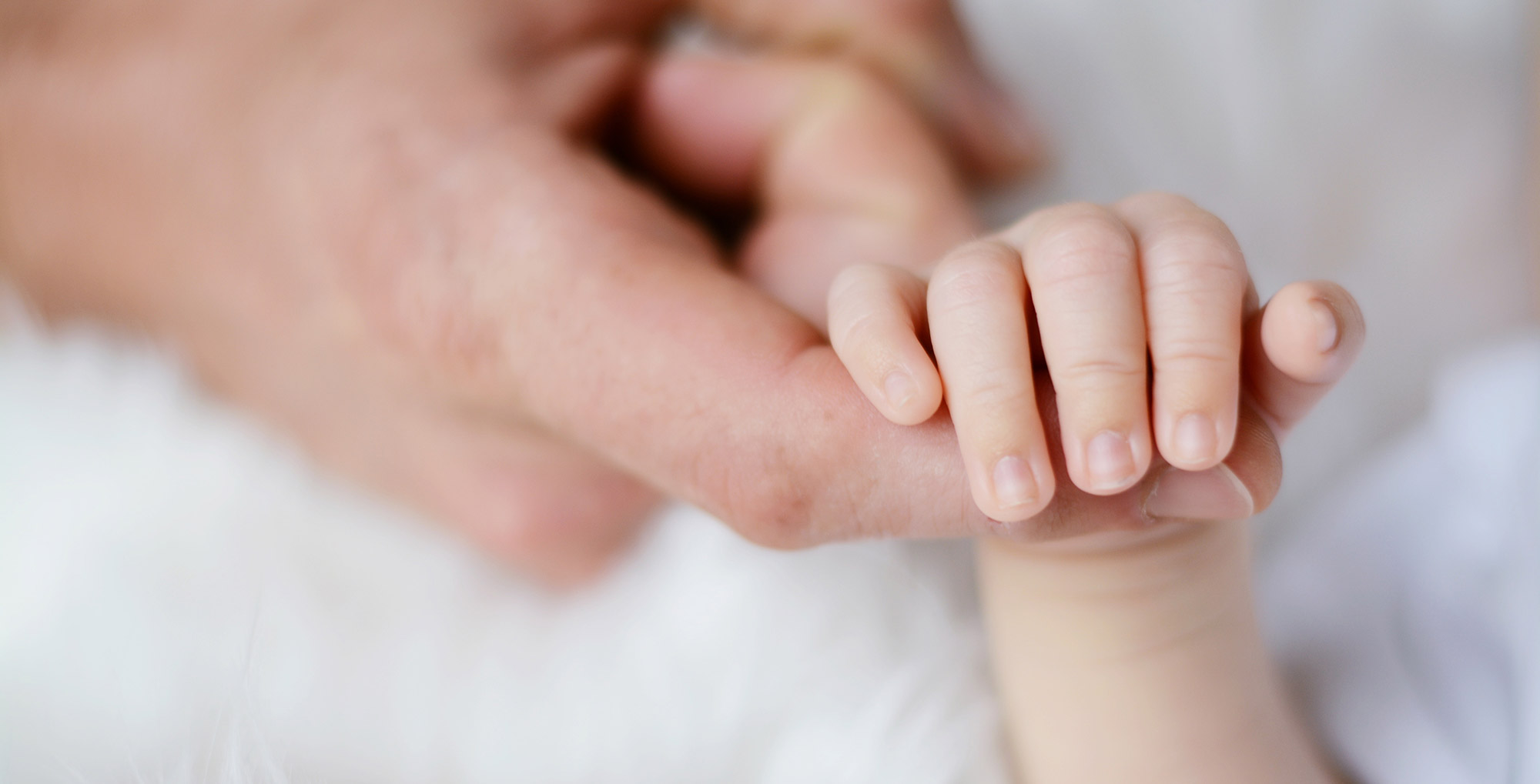 Mano del neonato che stringe il dito